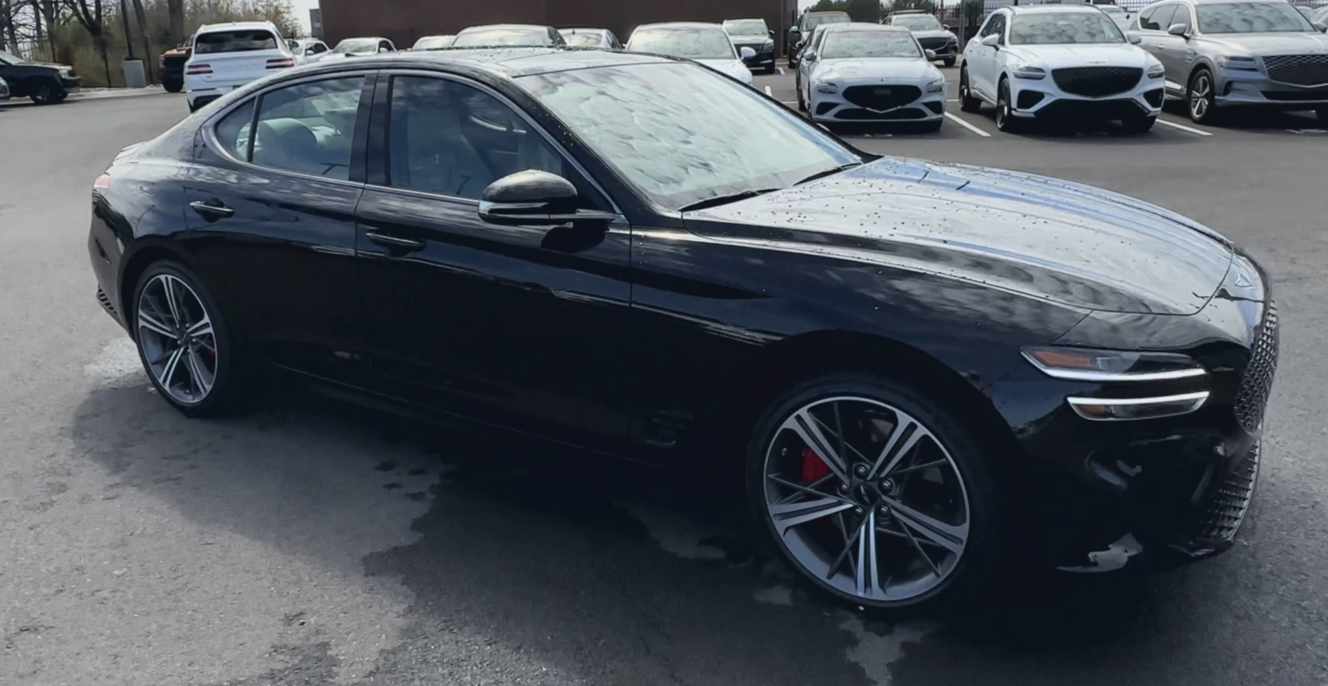 Black 2025 Genesis G70 sedan parked in dealership lot with sport wheels and sleek body design